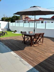 a table and two benches with an umbrella on a deck at Villa Pérola Pestana in Lourinhã