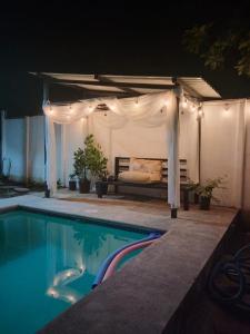 a bed under a canopy next to a pool at night at Cabañas Mantas in Tárcoles