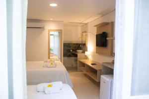 a hotel room with two beds and a bathroom at Suites Amma Noronha in Fernando de Noronha