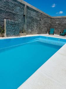 a blue swimming pool with two chairs and a brick wall at Sueño de Chicoana in Chicoana