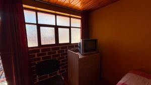 a bedroom with a tv on a dresser with a window at VillaHouse - Huaraz in Huaraz