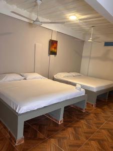 two twin beds in a room with wooden floors at Hotel Palmera Beach in Cartagena de Indias