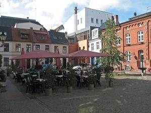 a group of tables and chairs with purple umbrellas at Courtyard Idyll Apartment in Rostock +26 photos