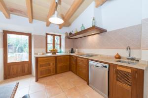 a kitchen with wooden cabinets and a sink and a dishwasher at Can Raia in Sóller