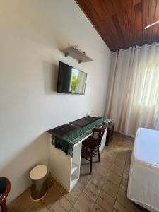 a room with a desk and a tv on the wall at POUSADA FAMILIAR - Perto do Aeroporto de Salvador in Lauro de Freitas
