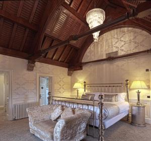 a bedroom with a bed and a couch and a chandelier at Fonab Castle Hotel in Pitlochry