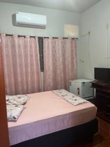 a small bedroom with a bed with pink curtains at ''Pousada Rosa Amiga'' in Barretos