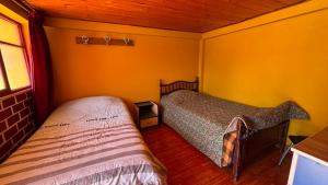 two beds in a room with yellow walls at VillaHouse - Huaraz in Huaraz