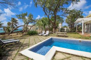 a swimming pool in a yard with chairs and a table at Stunning Views Oceanfront Oasis with Private Pool - Inch by Inch in Christ Church