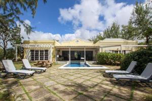 a house with a swimming pool and two lounge chairs at Stunning Views Oceanfront Oasis with Private Pool - Inch by Inch in Christ Church