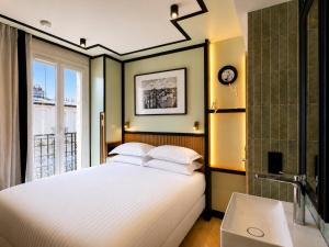 a bedroom with a bed and a sink and a window at Hotel Maison Lenoir in Paris