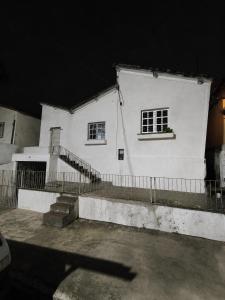 a white house with two windows and a fence at Suíte Completa com Tela de Cinema in Garanhuns
