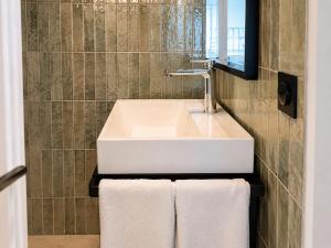 a bathroom with a sink and a mirror and towels at Hotel Maison Lenoir in Paris