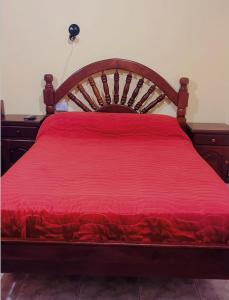 a wooden bed with a red bedspread on it at Hotel el Progreso in Olta