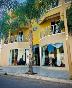 a palm tree in front of a yellow building at Hotel el Progreso in Olta