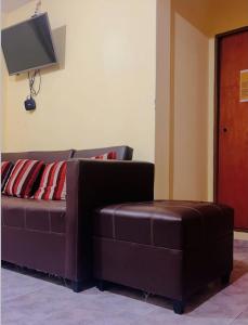a brown couch and a stool in a living room at Hotel el Progreso in Olta