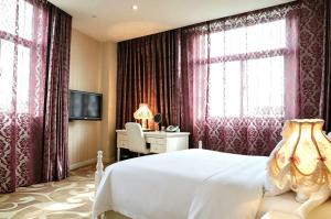 a bedroom with a white bed and a desk and windows at Dayi Yihao hotel in Xiamen