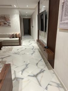 a living room with white marble floors and a television at belle appartement à centre Kénitra in Kenitra
