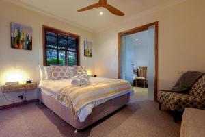 a bedroom with a bed and a chair and a window at BullerRoo Luxury Chalet & Cottage Farmstay in Barwite