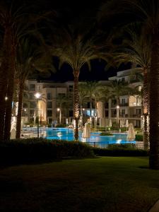 a pool at night with palm trees and a building at Marassi- Faya Residence in El Alamein