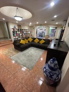 salon z czarną kanapą i żółtymi poduszkami w obiekcie Colonial la Estancia w mieście Reynosa