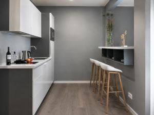 a kitchen with white cabinets and bar stools at THE ROOMS - Hotel & House in Frankfurt