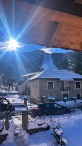 a house in the snow with the sun shining at Korja Apartments Mavrovo in Mavrovo
