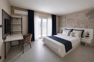 a bedroom with a bed and a desk and a television at TRYP by Wyndham Didim in Didim