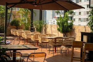 a patio with tables and chairs and an umbrella at Amana Hotel Phnom Penh in Phnom Penh