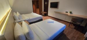 ein Hotelzimmer mit zwei Betten und einem Schreibtisch in der Unterkunft Kingston Hotel 28 - Gocos Hotel Klang in Klang