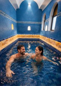 a man and a woman in a swimming pool at Riad ABBASSIA Marrakech Première - Authentic Medina Experience in Marrakesh +70 photos