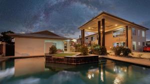 a house with a swimming pool at night at Western Downs Motor Inn in Miles