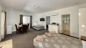 a hotel room with a bed and a kitchen and a table at Western Downs Motor Inn in Miles +49 photos