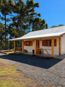 a small white house with a tin roof at Cabana Raízes da Mata - Hidro e Natureza in São Joaquim