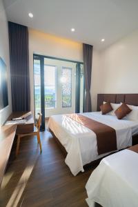 a bedroom with two beds and a desk and a window at LunaB Hotel in Dong Hoi