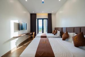 a hotel room with two beds and a television at LunaB Hotel in Dong Hoi
