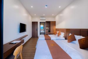 a hotel room with two beds and a television at LunaB Hotel in Dong Hoi