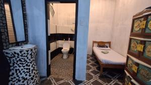 a bathroom with a toilet and a bed and a mirror at Bukit Lawang Orangutan Dormitory in Bukit Lawang