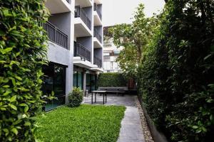 a garden with a bench in front of a building at We Grand Ever 9 in Nakhon Ratchasima