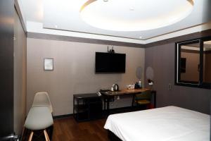 a bedroom with a bed and a desk and a tv at 진해프렌치코드호텔 in Chinhae