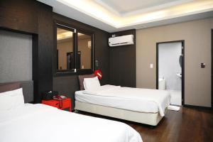 a hotel room with two beds and a bathroom at 진해프렌치코드호텔 in Chinhae