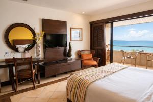 a hotel room with a bed and a desk and a television at Costabella Tropical Beach Hotel in Mactan
