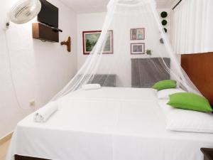 a bedroom with a white bed with green pillows at Entre Bosques Tayrona in Los Naranjos