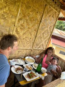 a group of people sitting at a table eating food at RM's Tourist Inn in Carmen +3 photos