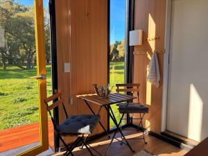 a table and chairs in a room with a large window at Tiny Home in the Hills by Tiny Away in Perth