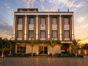 a large white building with trees in front of it at Hotel Starlink By The Nine Hotel in Jaipur