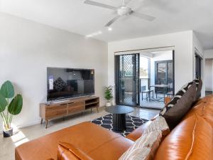 a living room with a brown leather couch and a flat screen tv at 3BR Top Floor Apartment with Parking, EV friendly & Views Brisbane South in Brisbane