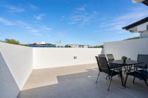 a patio with a table and chairs and a white wall at 3BR Top Floor Apartment with Parking, EV friendly & Views Brisbane South in Brisbane
