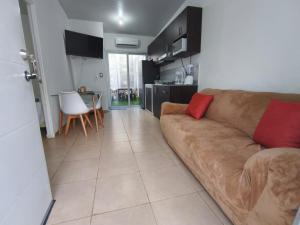 a living room with a brown couch with two red pillows at Hermosa casa con piscina in Sitio del Niño