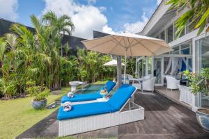 a patio with two blue chairs and an umbrella at Hidden Hills Villas - Small Luxury Hotels of The World in Uluwatu